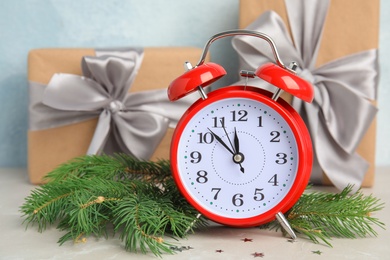 Alarm clock, fir branches and gifts on table. Christmas countdown