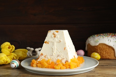 Photo of Traditional cottage cheese Easter paskha with dried apricot on wooden table