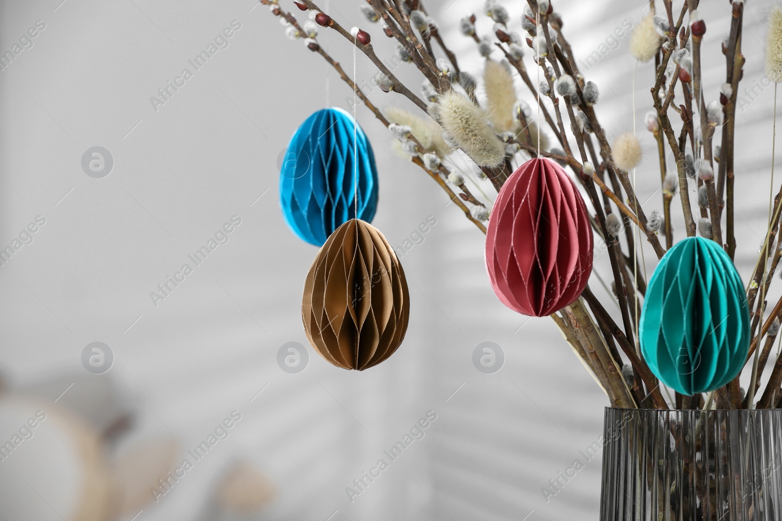 Photo of Beautiful pussy willow branches with paper eggs in vase at home, closeup and space for text. Easter decor