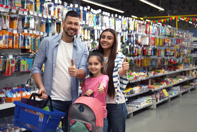 Family with little girl at section with school stationery in supermarket