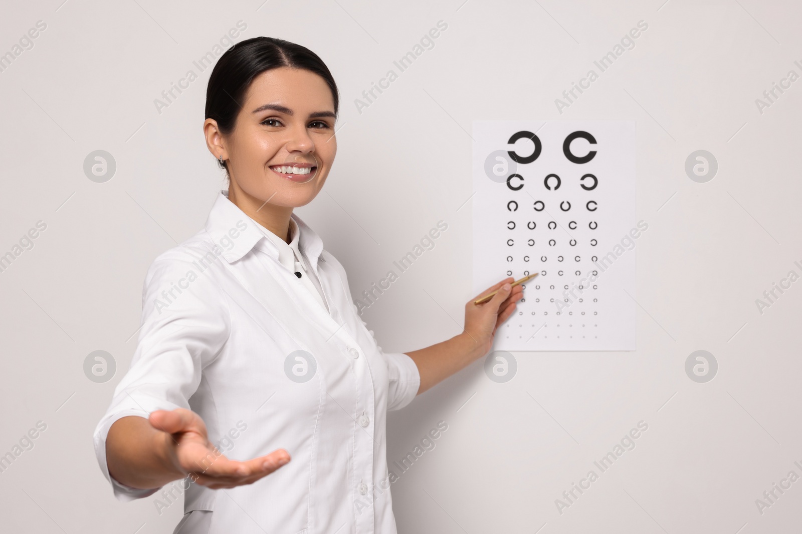 Photo of Ophthalmologist pointing at vision test chart on white wall