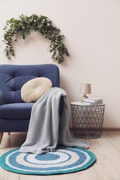 Photo of Stylish room decorated with beautiful eucalyptus garland above comfortable armchair