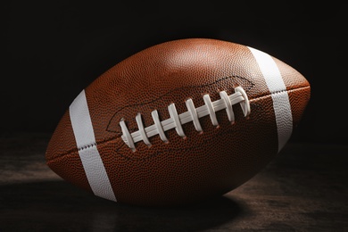 Photo of New American football ball on table against dark background