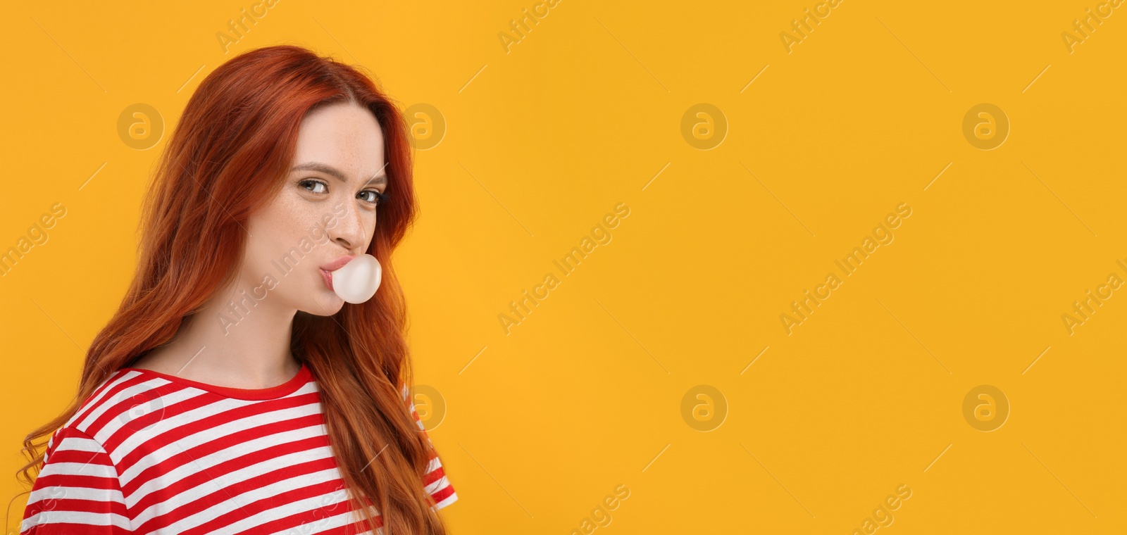 Photo of Portrait of beautiful woman blowing bubble gum on orange background. Space for text