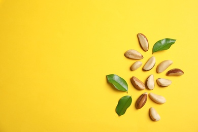 Photo of Flat lay composition with Brazil nuts, leaves and space for text on color background