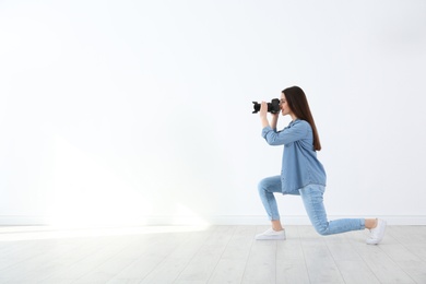 Photo of Female photographer with camera near light wall indoors