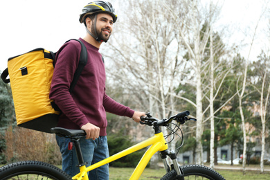 Courier with thermo bag and bicycle outdoors. Food delivery service