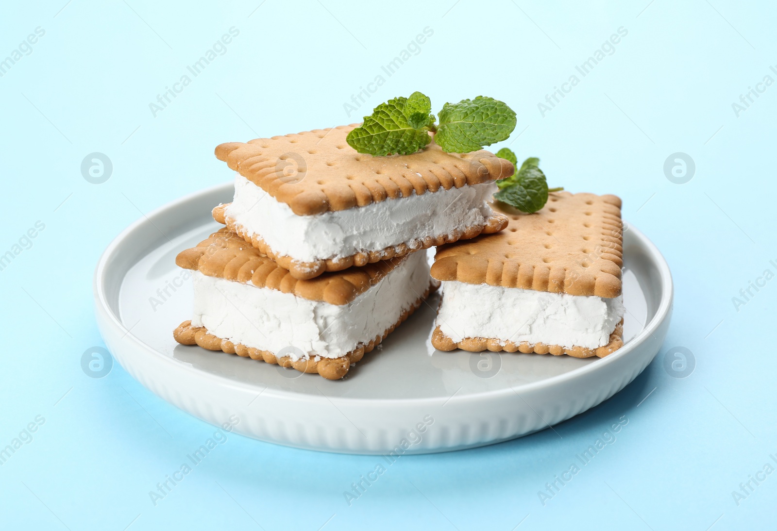 Photo of Sweet delicious ice cream cookie sandwiches on light blue background