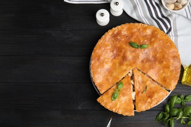 Photo of Delicious meat pie served on black wooden table, flat lay. Space for text