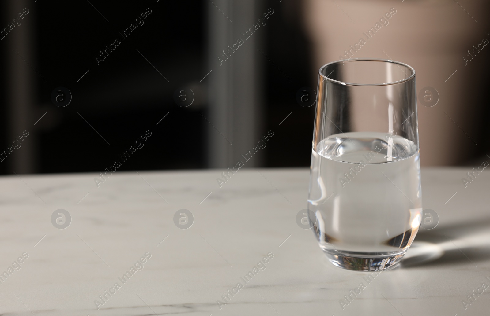 Photo of Glass of pure water on white table indoors, space for text