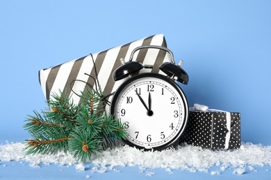 Photo of Vintage alarm clock with Christmas decor on light blue background. New Year countdown