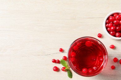 Photo of Tasty refreshing cranberry juice, mint and fresh berries on light wooden table, flat lay. Space for text