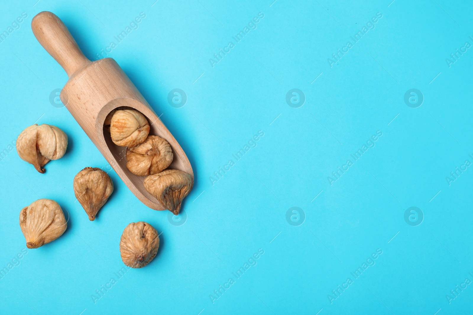 Photo of Scoop of dried figs on color background, top view with space for text. Healthy fruit