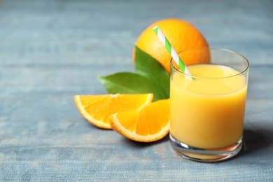 Photo of Glass of orange juice and fresh fruits on wooden table, closeup. Space for text