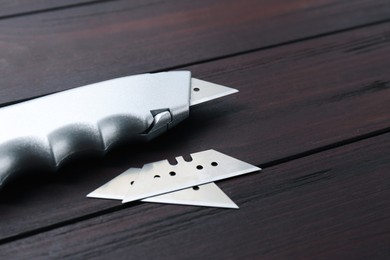 Photo of Utility knife and blades on wooden table, closeup. Space for text