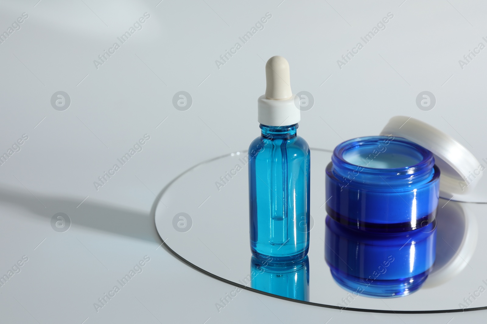 Photo of Bottle and jar with cosmetic products on light background, space for text