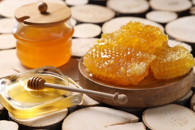 Natural honeycombs with honey and wooden dipper on textured table, closeup