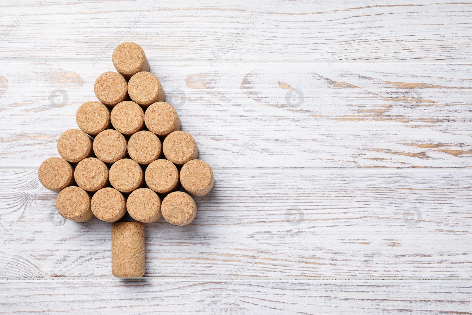 Photo of Christmas tree made of wine corks on white wooden table, top view. Space for text