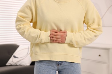 Woman suffering from abdominal pain at home, closeup. Unhealthy stomach