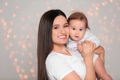 Photo of Portrait of young mother and her adorable baby against defocused lights