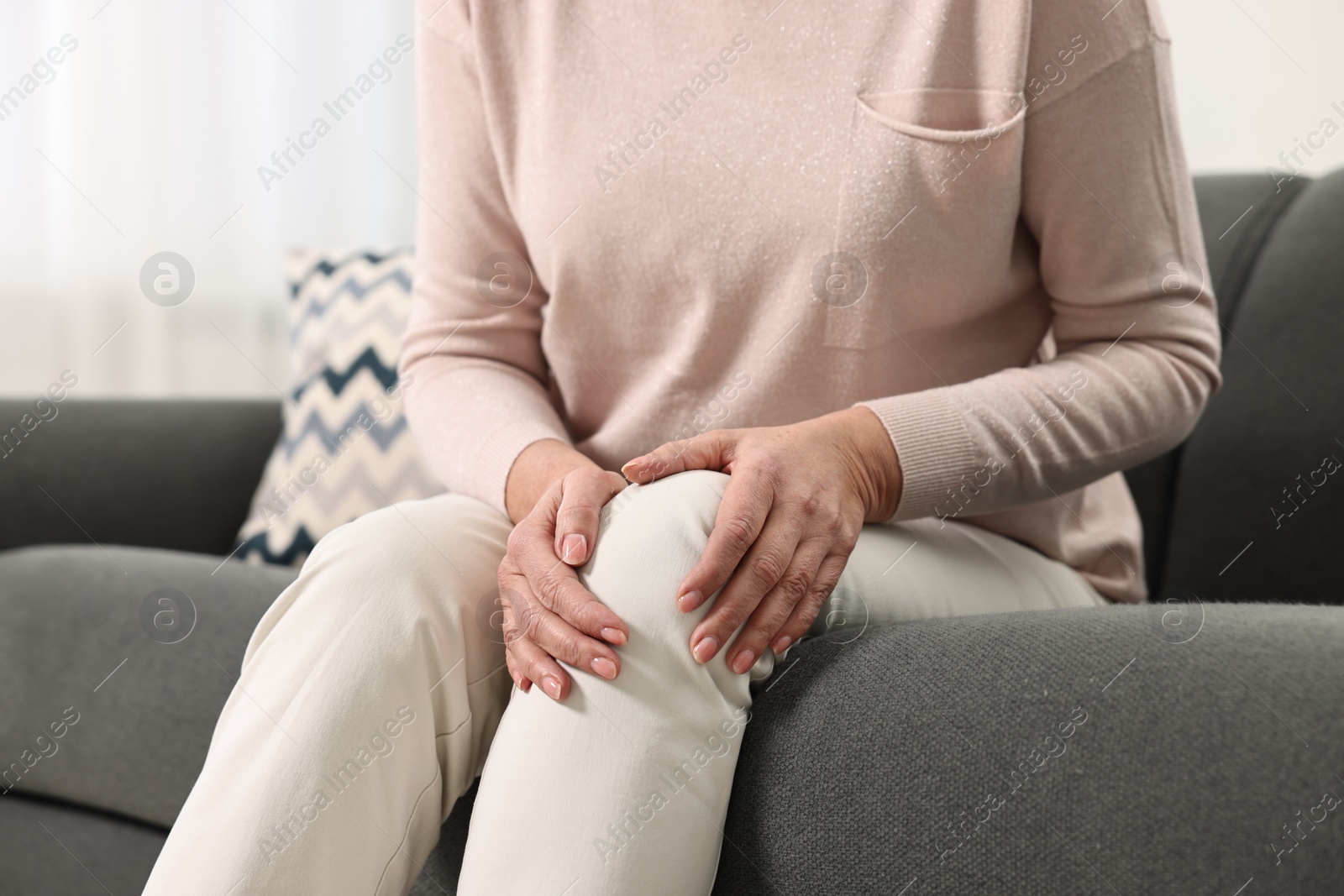 Photo of Arthritis symptoms. Woman suffering from pain in knee at home, closeup