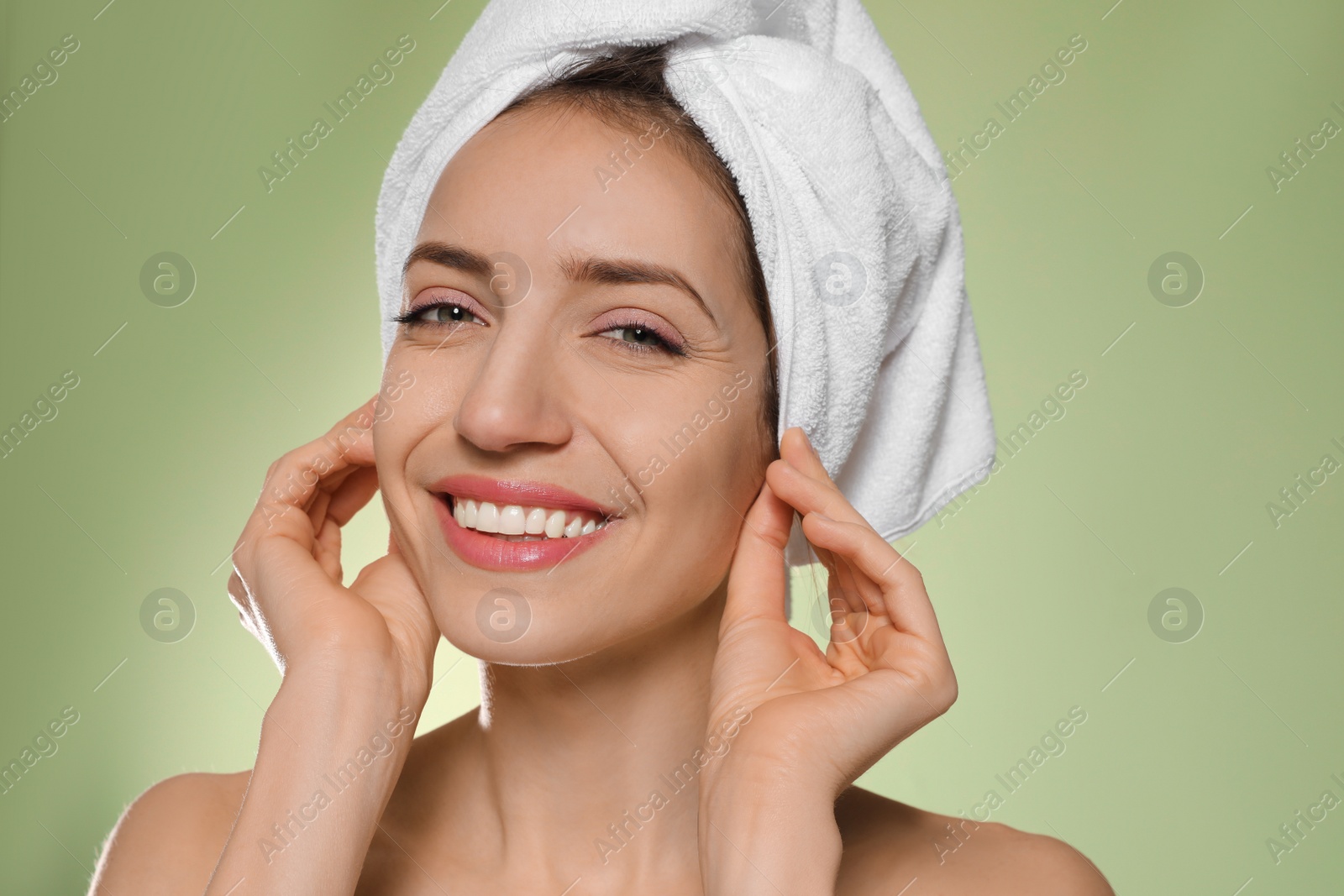 Photo of Beautiful young woman with hair wrapped in towel after washing on light green background