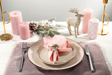 Photo of Stylish table setting with pink fabric napkin, beautiful decorative ring and festive decor on white wooden background