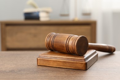 Photo of Wooden gavel and sound block on table indoors, closeup. Space for text