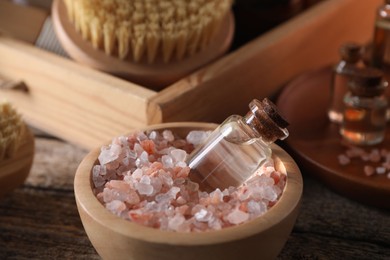 Spa treatment. Sea salt and bottle of essential oil in bowl on table, closeup