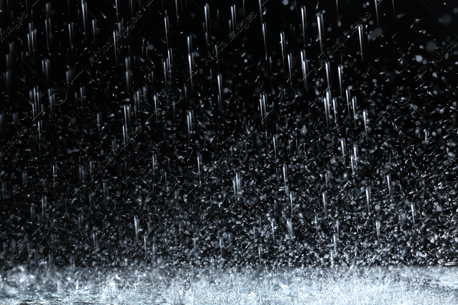 Photo of Heavy rain falling down on ground against dark background