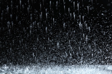 Photo of Heavy rain falling down on ground against dark background