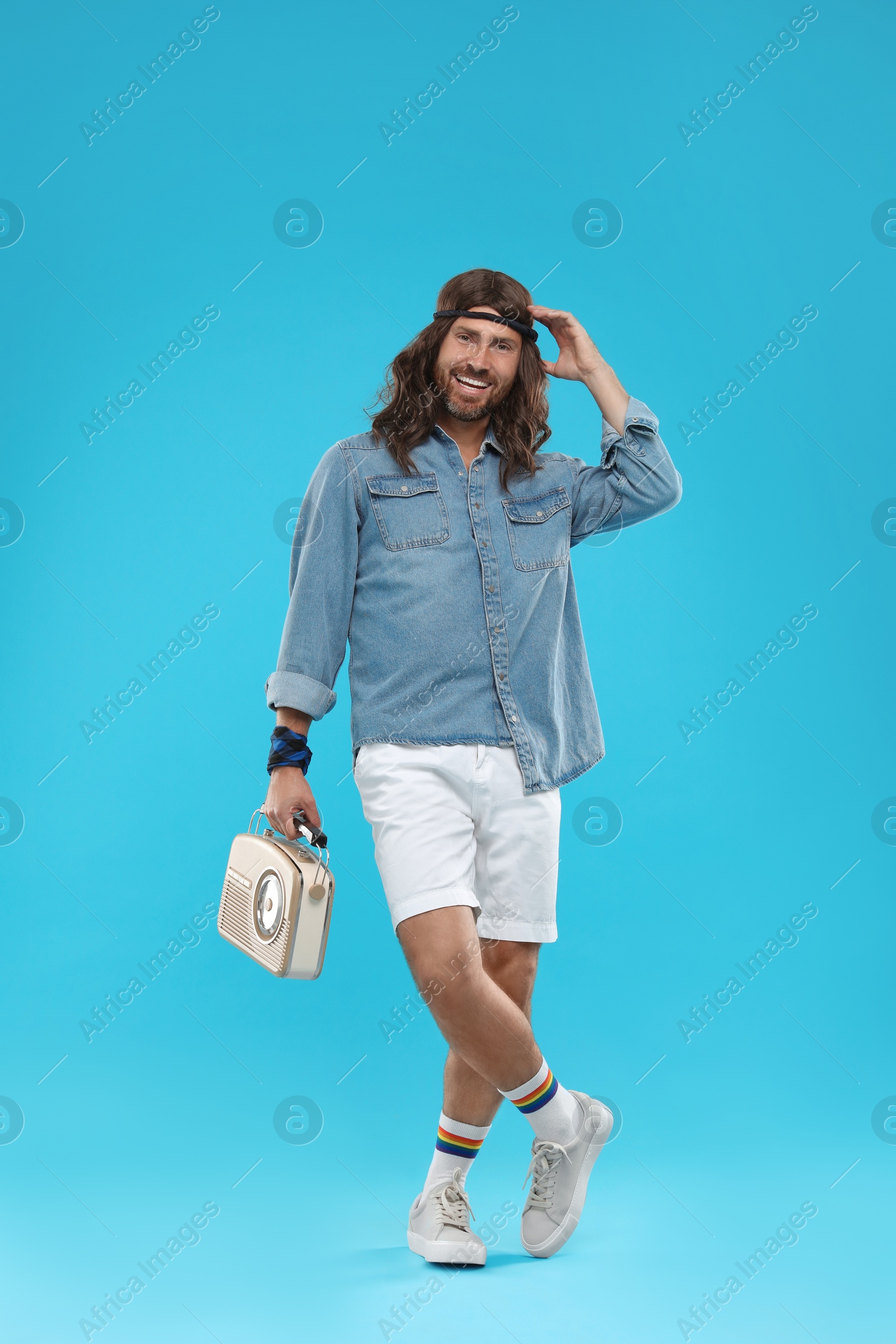 Photo of Stylish hippie man with retro radio receiver on light blue background