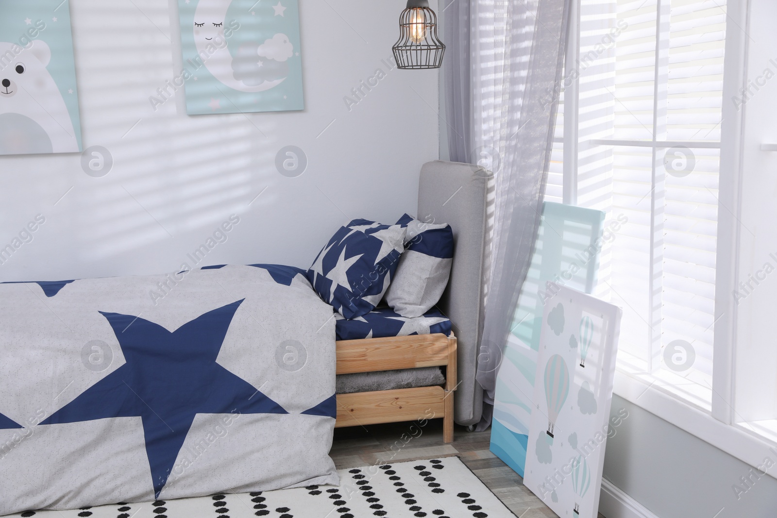 Photo of Bed with stylish linens in children's room. Interior design