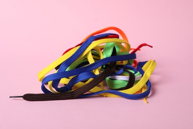 Photo of Many colorful shoe laces on light pink background