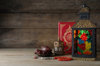 Photo of Composition with Arabic lantern and quran on wooden table. Space for text