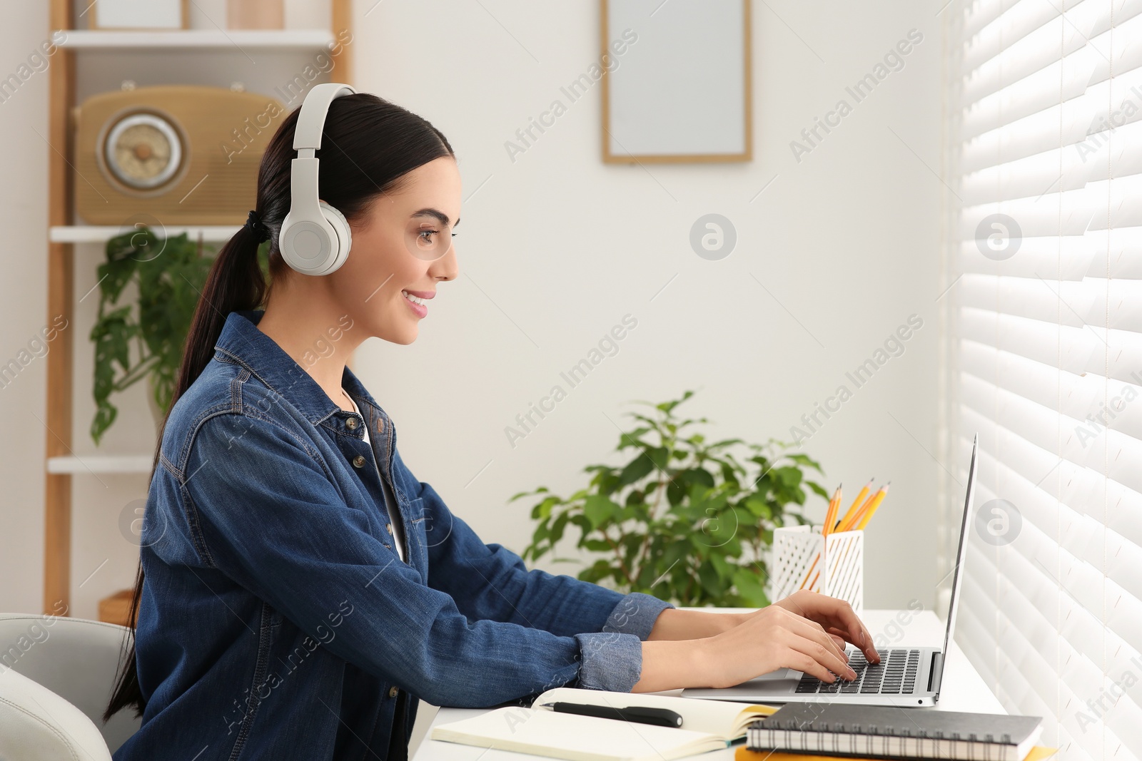 Photo of Online translation course. Student in headphones typing on laptop at home