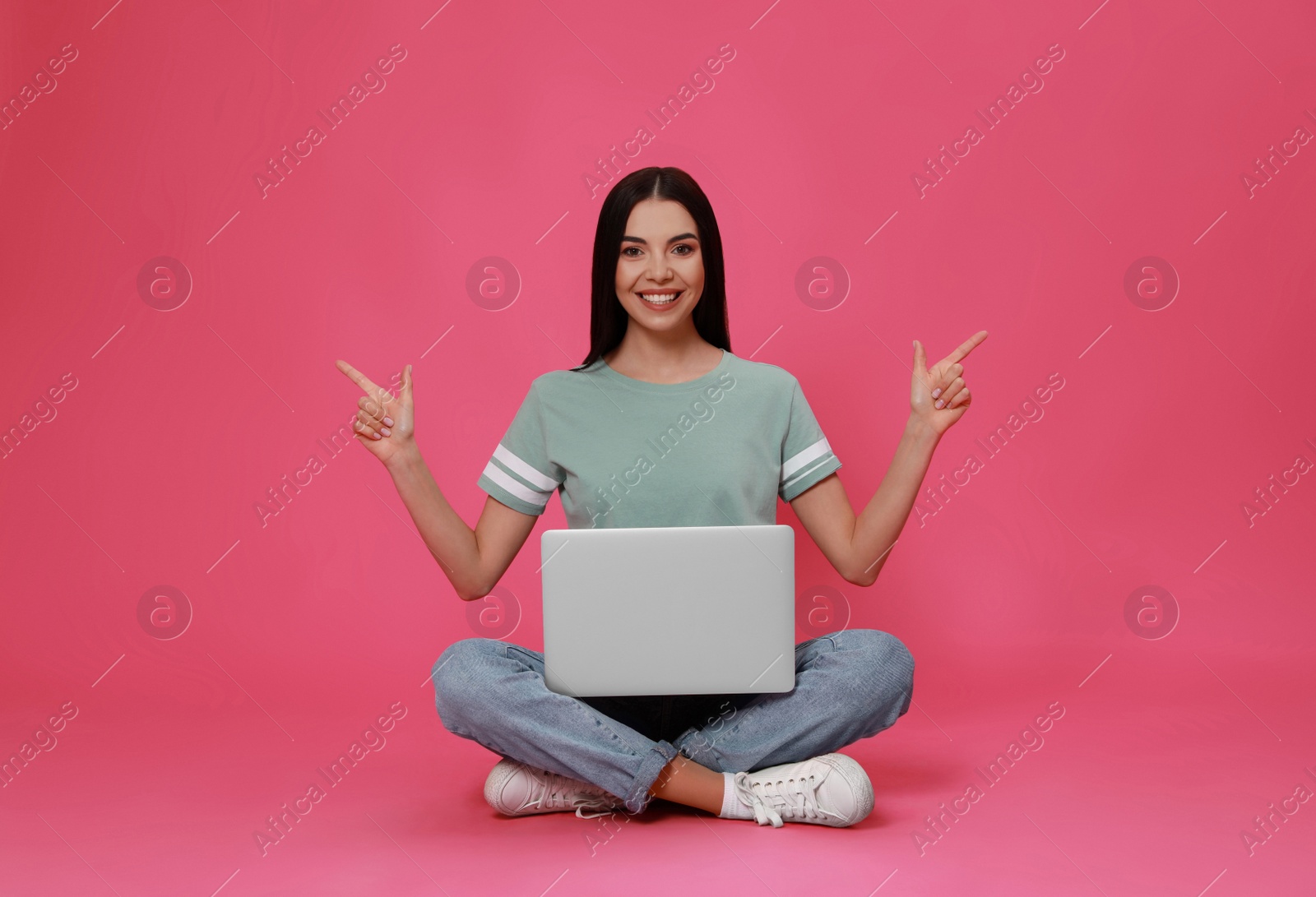 Photo of Young woman with modern laptop on pink background