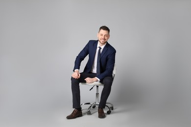 Photo of Handsome businessman sitting in office chair on grey background