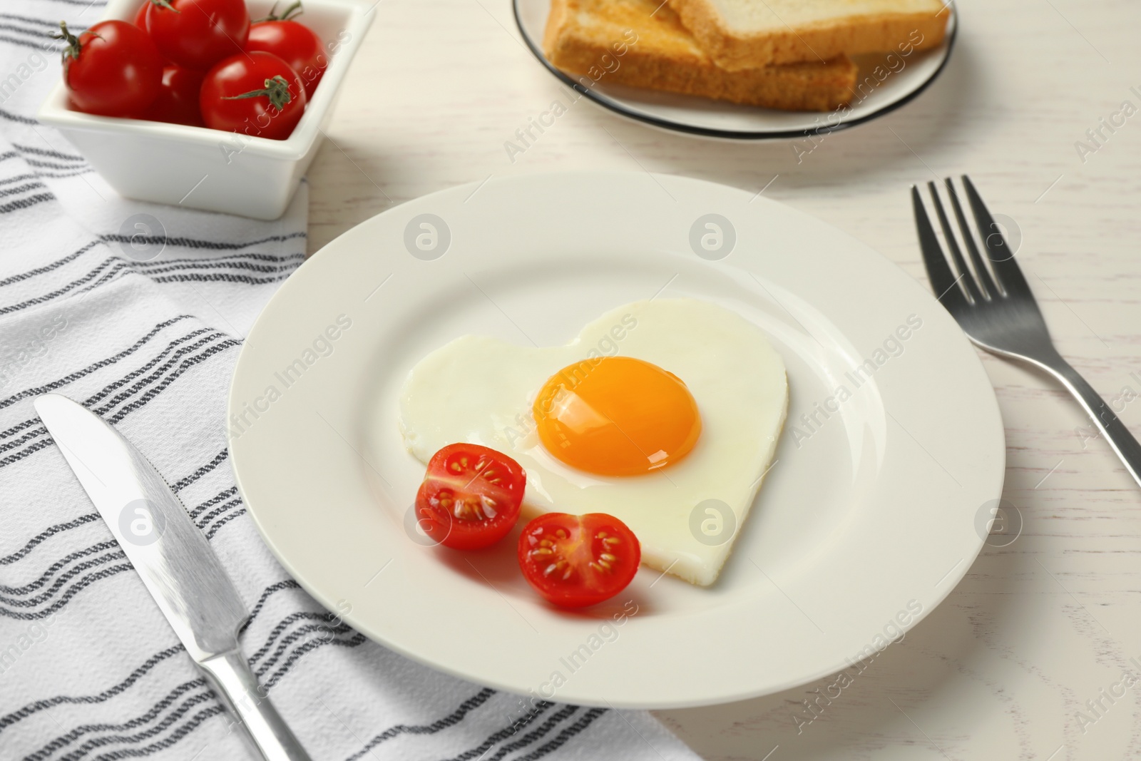 Photo of Heart shaped fried egg served on white wooden table