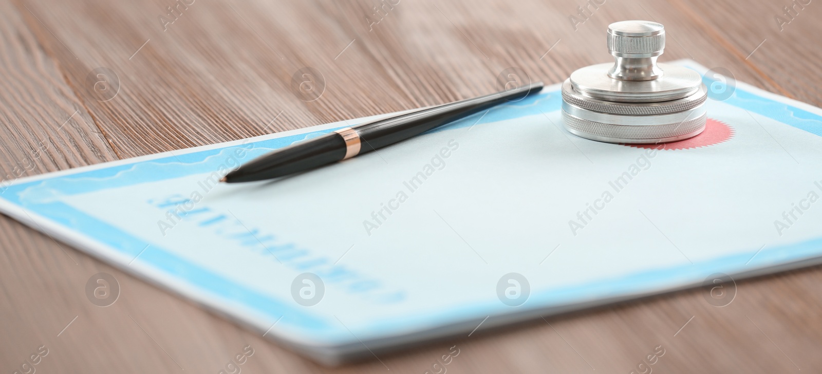 Image of Certificate form, notary stamp and pen on wooden table, closeup. Banner design