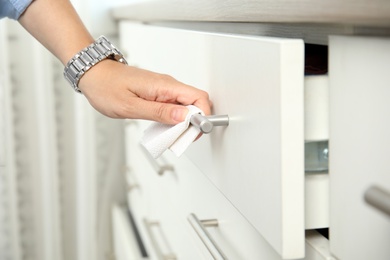 Photo of Woman using tissue paper to open drawer, closeup