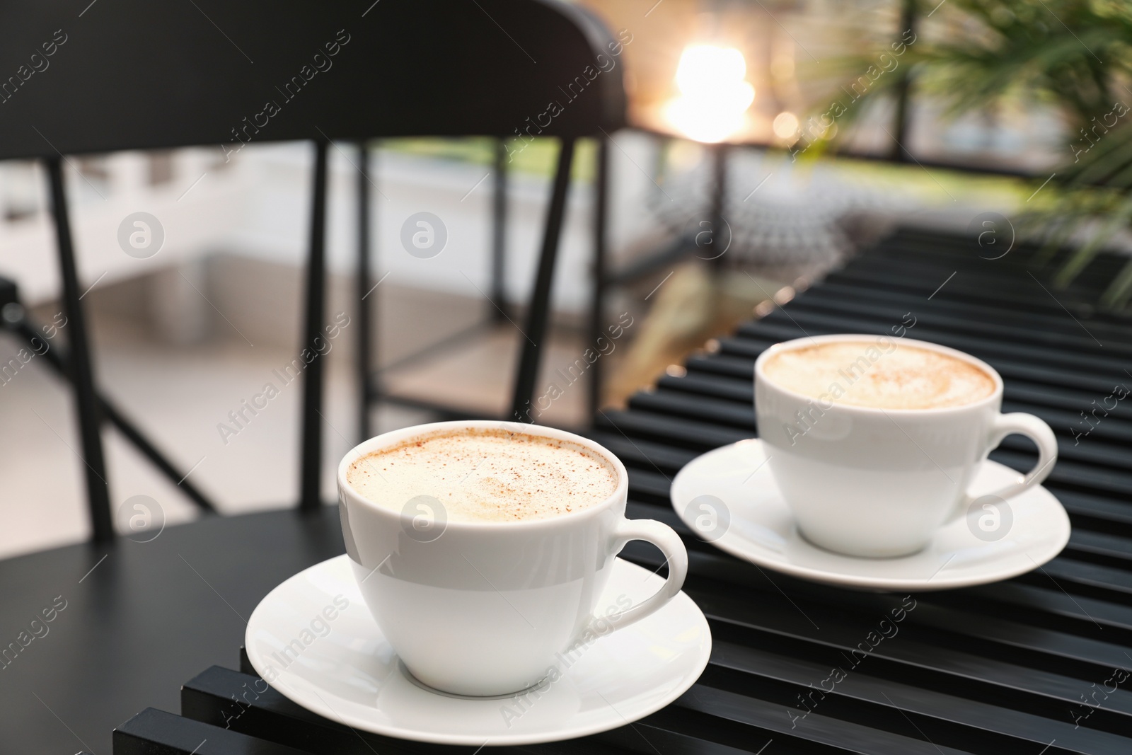 Photo of Ceramic cups of aromatic coffee with foam on wooden table in cafe