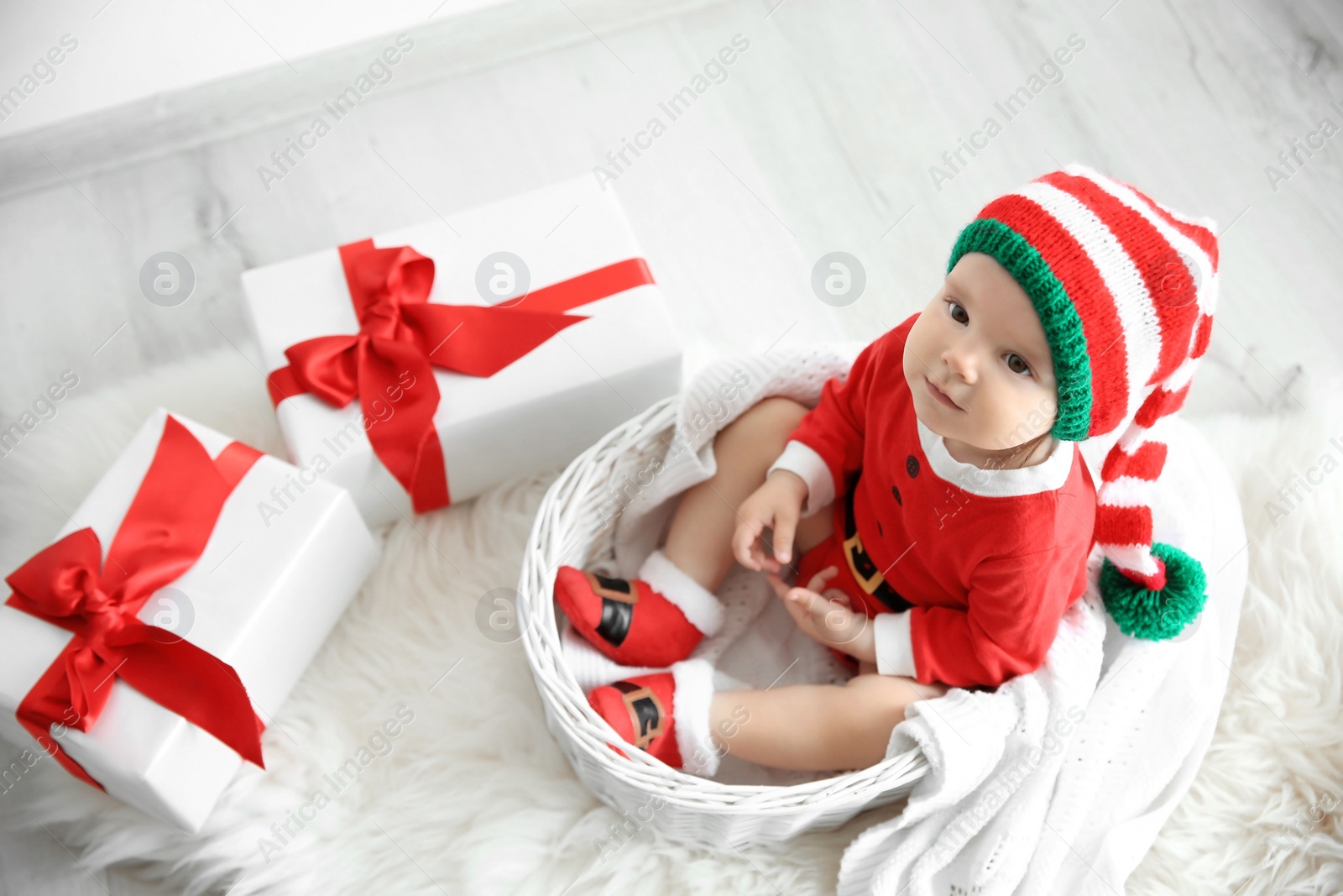 Photo of Cute little baby wearing Christmas costume in basket at home