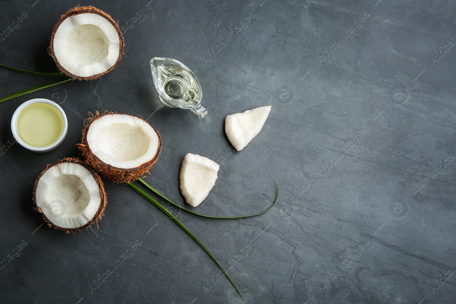 Photo of Flat lay composition with natural organic oil and coconuts on grey stone background, flat lay. Space for text