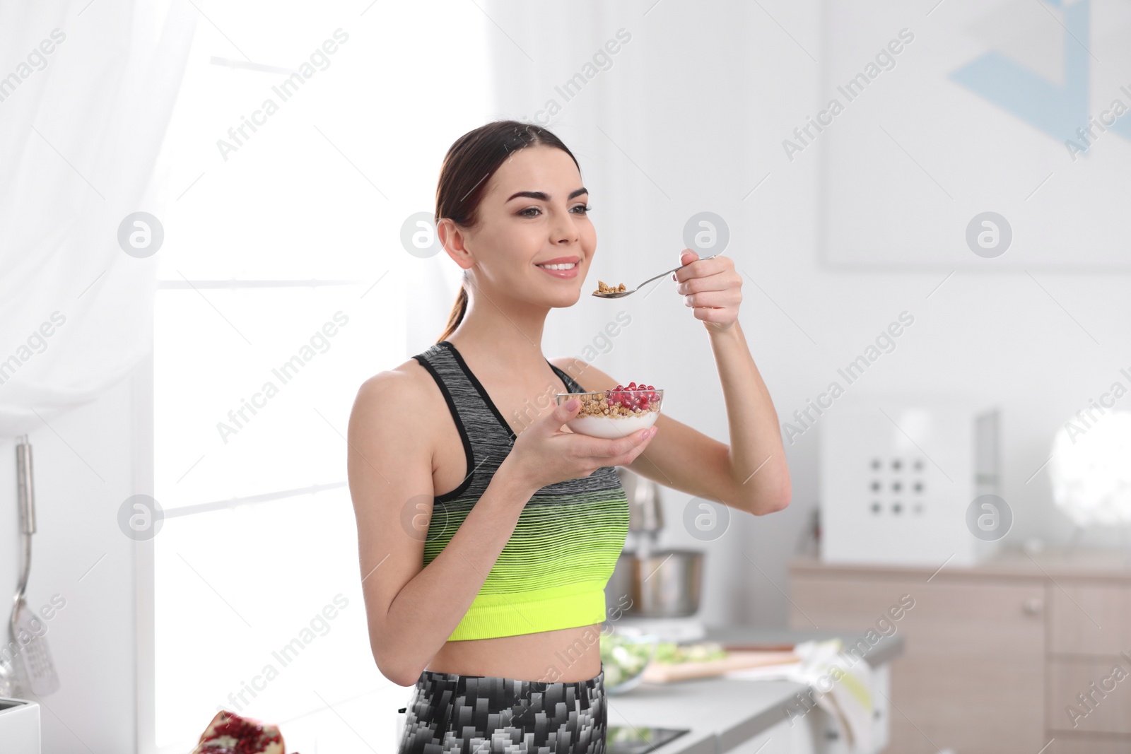 Photo of Young woman in fitness clothes having healthy breakfast at home