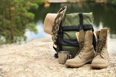 Photo of Set of camping equipment on rock near lake