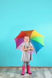 Little girl with rainbow umbrella near color wall