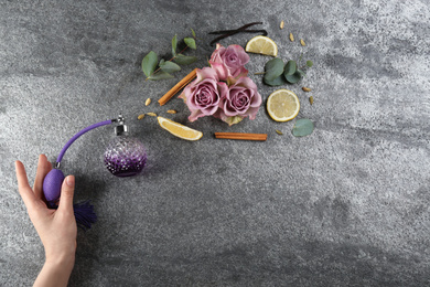 Photo of Woman with perfume. Fragrance composition, flowers and lemon on grey background,  top view. Space for text