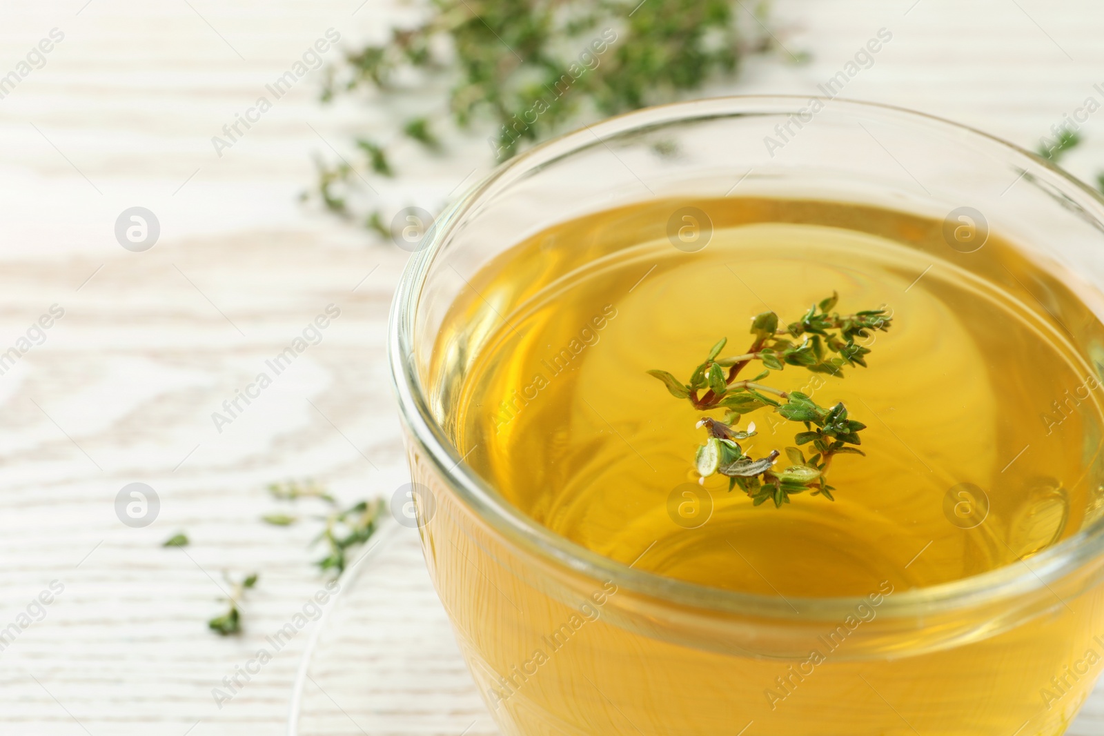 Photo of Aromatic herbal tea with thyme on white wooden table, closeup. Space for text