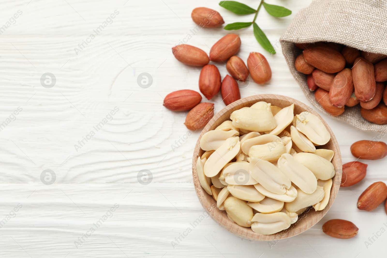 Photo of Fresh peanuts and twig on white wooden table, flat lay. Space for text